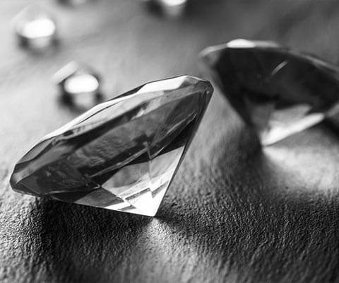 Several loose round cut diamonds on a black table.